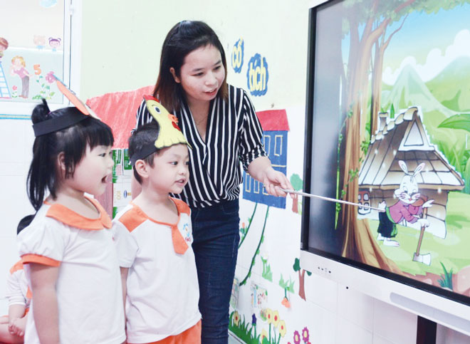 Cô Nguyễn Thị Thanh dạy học sinh nhận biết các con vật thông qua hình ảnh trên máy chiếu. Ảnh: NGỌC PHÚ