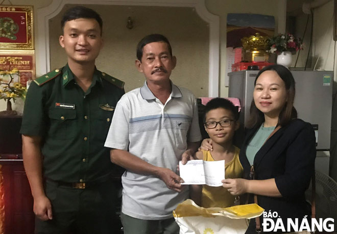 Thiếu úy Nguyễn Quang Chánh (bìa trái) trao hỗ trợ cho gia đình cháu Đặng Văn Long.  Ảnh: THẢO NGUYÊN	