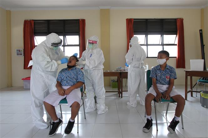 Nhân viên y tế lấy mẫu xét nghiệm COVID-19 cho học sinh tại Surakarta, Trung Java, Indonesia, ngày 14/10/2021. Ảnh: THX/TTXVN