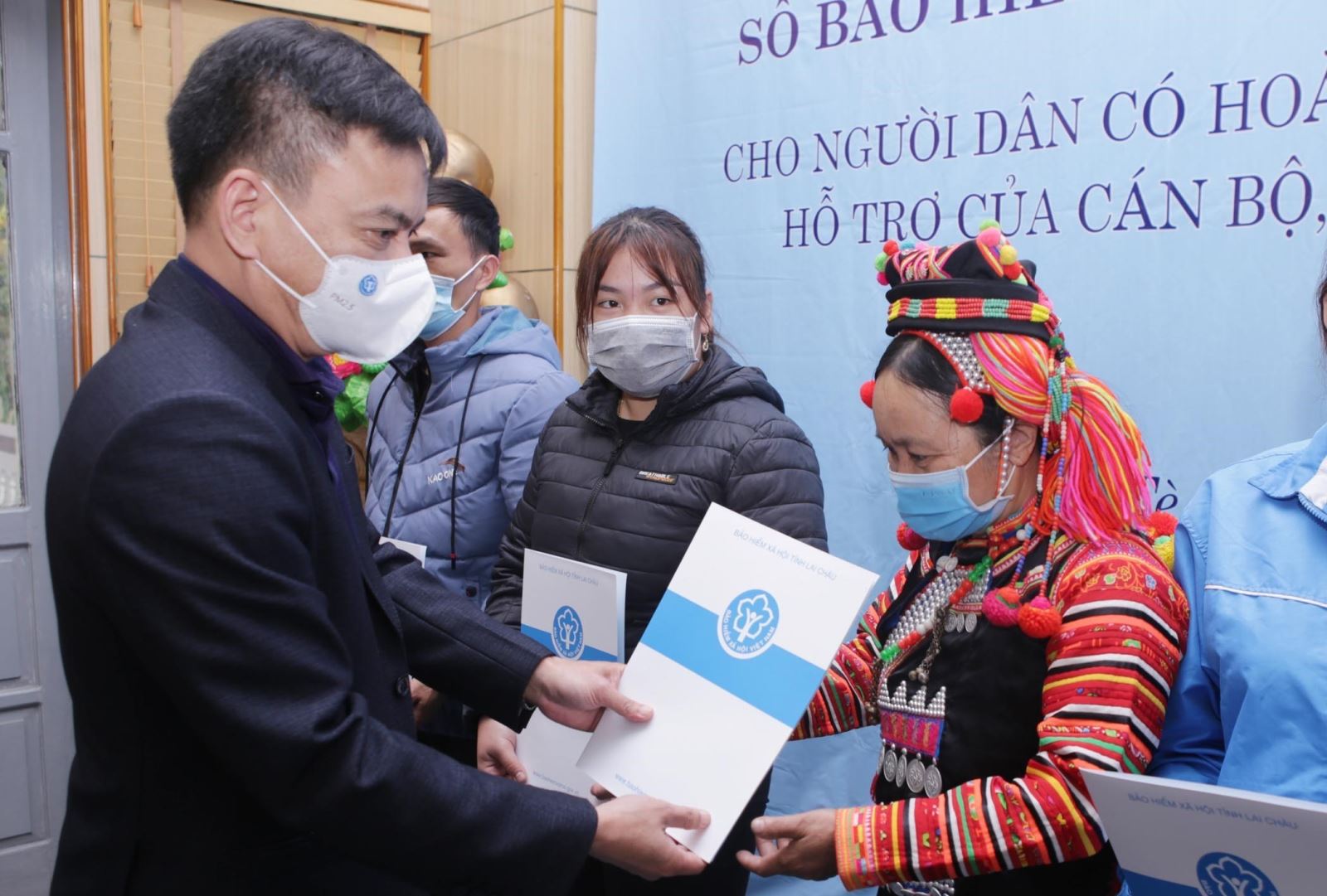 Phó Giám đốc BHXH tỉnh Lai Châu, Dương Quốc Tuấn trao sổ BHXH và thẻ BHYT cho các hộ dân nghèo có hoàn cảnh đặc biệt khó khăn của huyện biên giới Mường Tè (Lai Châu). Ảnh: Quý Trung/TTXVN