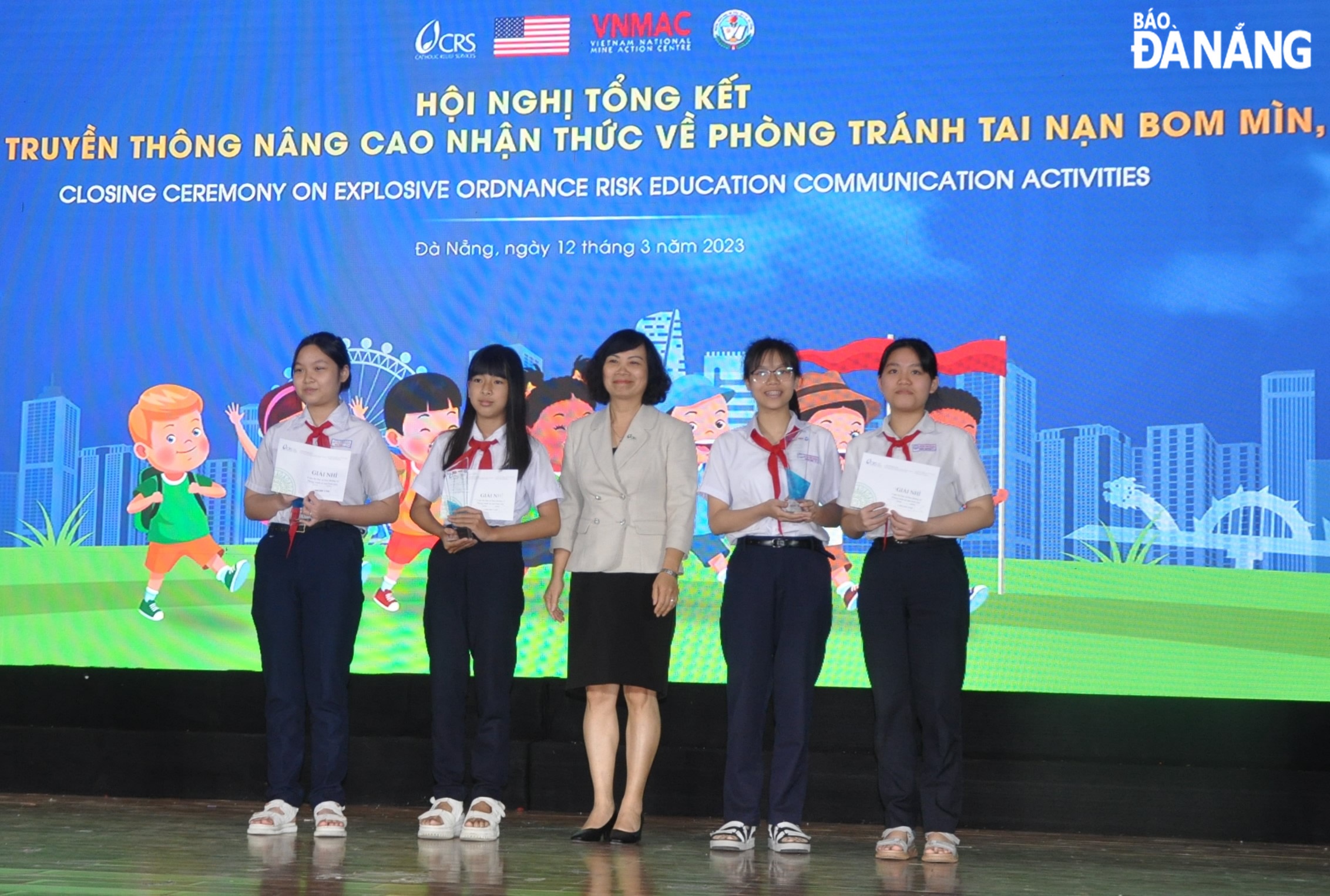 Trưởng đại diện Tổ chức CRS tại Việt Nam Đào Thị Hồng (giữa) trao thưởng cho những học sinh đạt giải tại cuộc thi “Đại sứ học đường trong tuyên truyền phòng tránh tai nạn bom mìn, vật nổ do chiến tranh để lại”. Ảnh: LÊ HÙNG