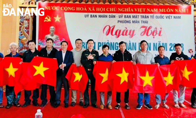 Đại tá Nguyễn Thanh Thủy (thứ 5, bên trái sang) tặng cờ Tổ quốc, động viên ngư dân phường Mân Thái, quận Sơn Trà bám biển sản xuất. Ảnh: B.V