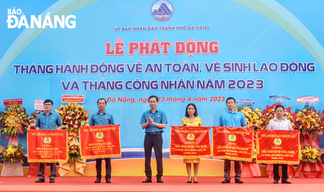 Chủ tịch Liên đoàn Lao động  thành phố Nguyễn Duy Minh trao cờ thi đua của Tổng Liên đoàn Lao động  Việt Nam cho 5 tập thể có thành tích xuất sắc trong phong trào thi đua lao động giỏi và xây dựng tổ chức Công đoàn vững mạnh năm 2022, tại lễ phát động Tháng Công nhân năm 2023. Ảnh: PHƯƠNG TRÀ