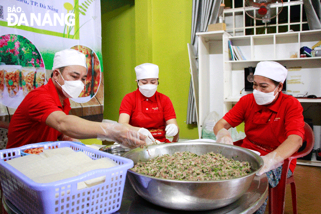 Anh Nguyễn Hùng Mạnh (bên trái) cùng người trong gia đình chế biến thực phẩm phục vụ các đơn đặt hàng. Ảnh: X.D	