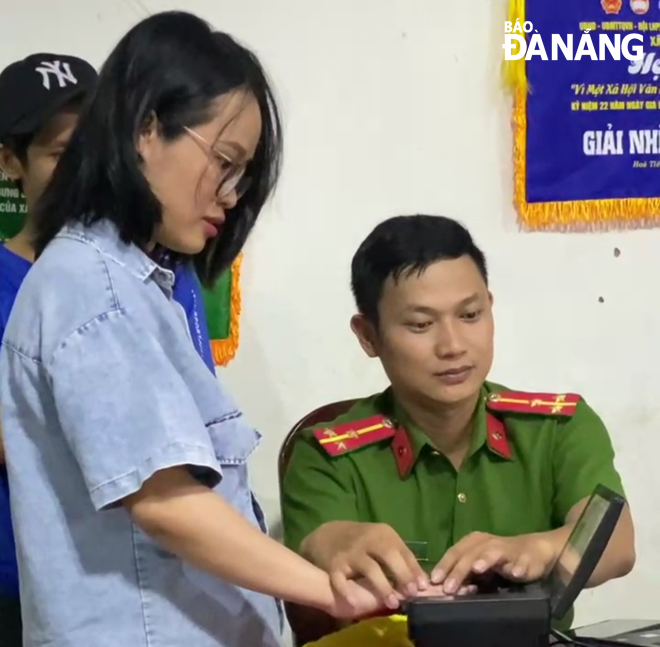 Thượng úy Trần Hữu Tuyết (bìa phải) làm định danh điện tử mức độ 2 cho người dân xã Hòa Tiến.