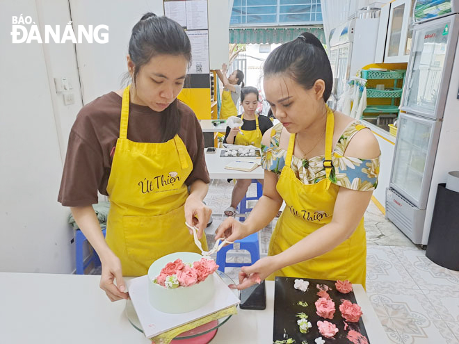 Cô giáo Dương Nguyễn Ngọc Thiên (bên phải) hướng dẫn học trò cách tạo hình một chiếc bánh kem đẹp. Ảnh: KHÁNH HÒA