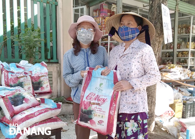 Bà Phan Thị Ngọc Hà (bên trái) hỗ trợ gạo cho các hộ khó khăn trong tổ.