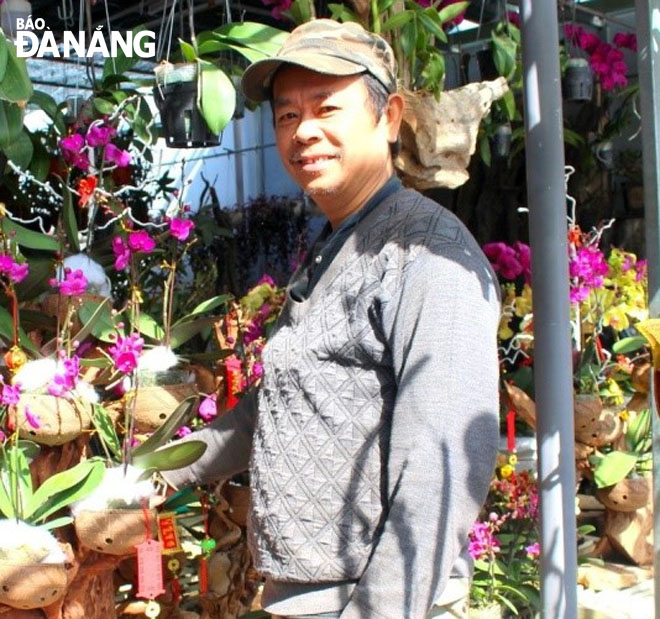 Ông Nguyễn Văn Tịnh cùng tác phẩm lan ghép trên gỗ lũa của mình.