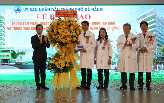 Bí thư Thành ủy Nguyễn Văn Quảng (bên trái) tặng hoa chúc mừng tập thể Bệnh viện Đà Nẵng khi tiếp nhận 2 công trình y tế chuyên sâu. Ảnh: PHAN CHUNG