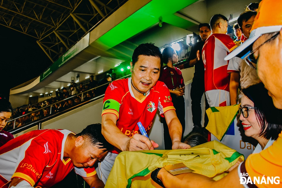 Vietnamese football legend Nguyen Hong Son and other players sign jerseys for fans during the break